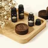 Diffuseur d'huiles essentielles en noyer noir avec flacons d'huiles, tray en bois naturel et éléments de décoration.