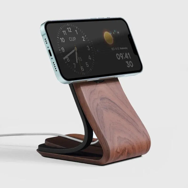 Wooden MagSafe phone stand with sleek design, featuring a charging cable and a smartphone displaying a clock.