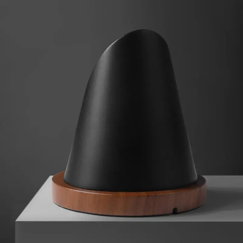 Black charging tip with wooden base, designed for MagSafe by Station de charge.