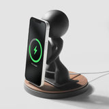Black figurine phone stand with wireless charging capability and wooden base