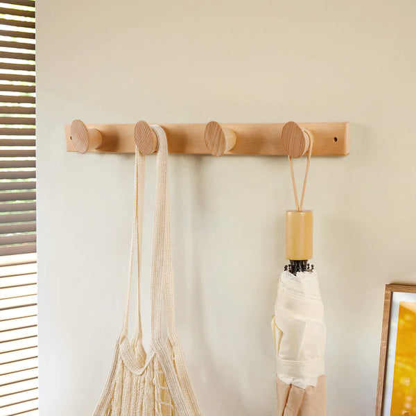 Crochet mural coat rack in walnut by Frêne, featuring natural wood design with four rounded hooks.