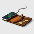 Wooden wireless charger with smartphone, brown leather coin holder, and coins.