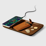 Wooden wireless charger with smartphone, brown leather coin holder, and coins.