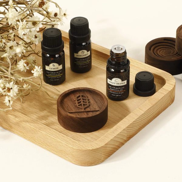 Diffuseur d'huiles essentielles en noyer noir avec flacons d'huiles, tray en bois naturel et éléments de décoration.